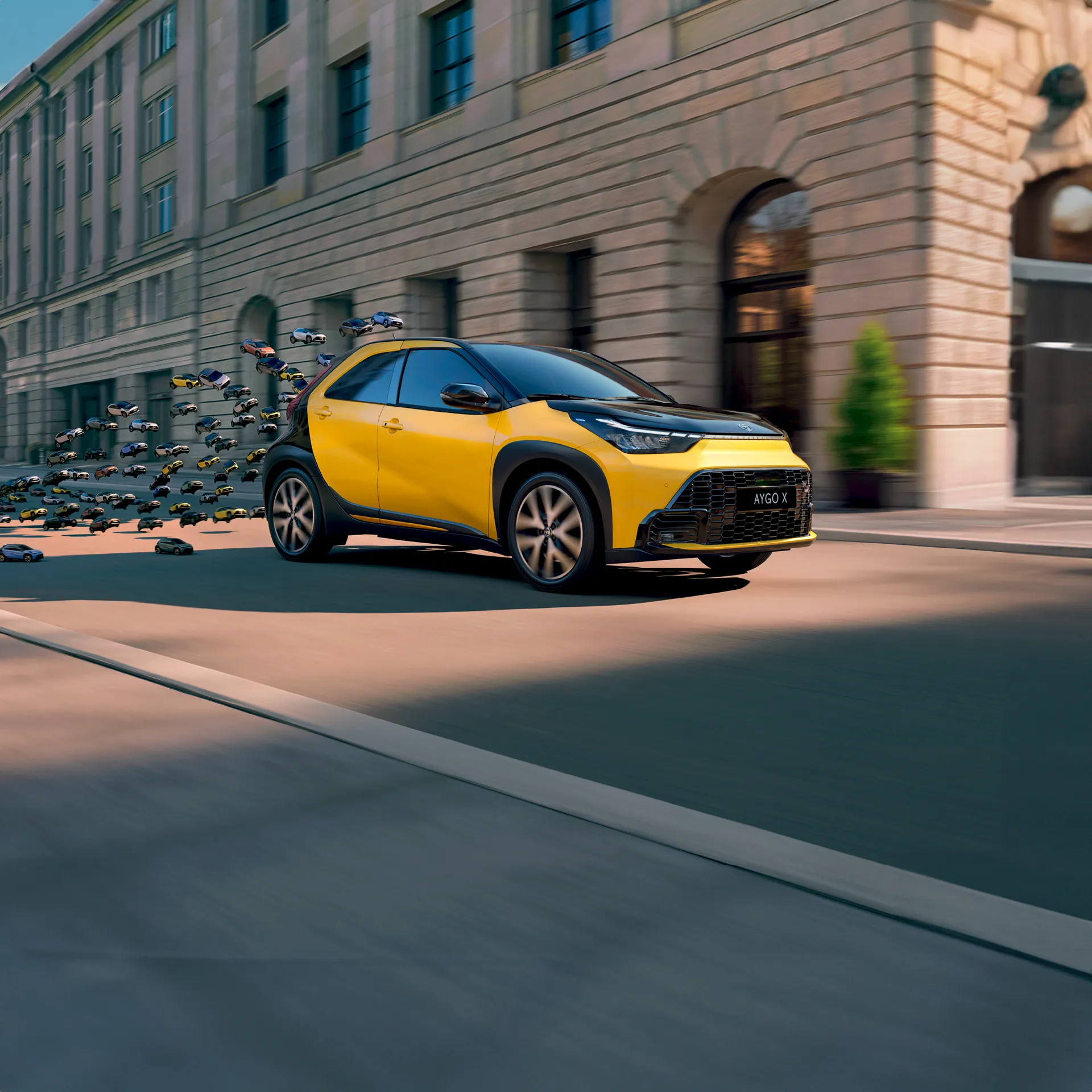 Toyota Aygo X gialla e nera su strada rincorsa da tante piccole aygo x