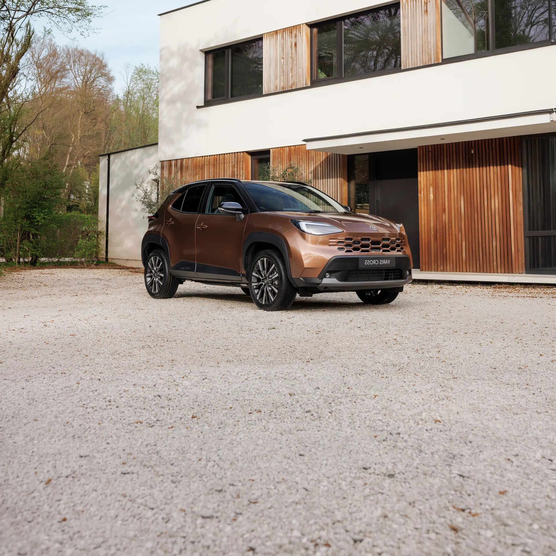 nuova toyota yaris cross color rame parcheggiata davanti a casa moderna